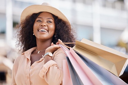 Woman smiling brightly while holding several shopping bags