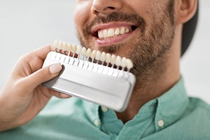 Dentist comparing several dental veneers to a patient’s smile