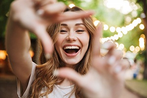 Woman forming a box around her smile with her fingers