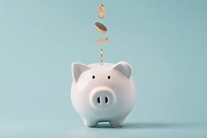Coins dropping into a white piggy bank on a blue background